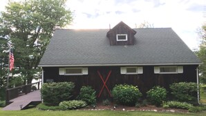 A wooden building with a dark roof, a small dormer window, and a red 'X' on the front wall. - Charming Lakefront Cottage - Northern Lake George (Ticonderoga)