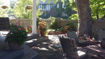 An outdoor patio area with stone flooring, potted plants, and outdoor furniture.