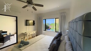 A bedroom with a bed, a desk, a chair, a television, and a large window.