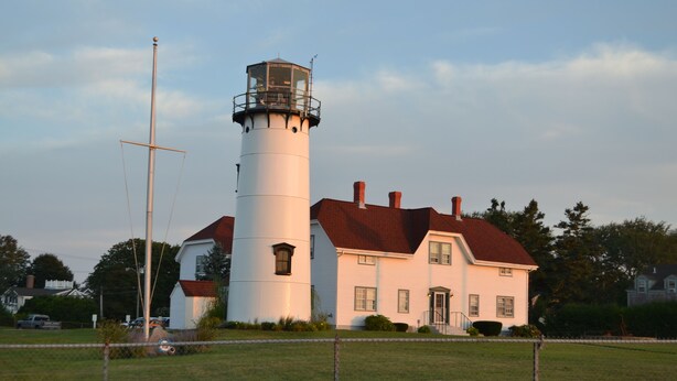 A lighthouse with a cylindrical tower and a white building with a red roof. - Quaint & Cozy Downtown Chatham Home, Walk to Town and Beaches (Chatham)