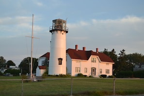 A lighthouse with a cylindrical tower and a white building with a red roof.