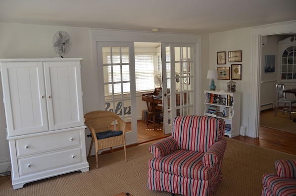 A living room with a white cabinet, striped armchair, and a wicker chair.