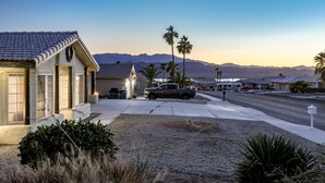 A residential street with houses, a parked truck, and palm trees. - Spacious 3+3 w/ Pool & Game room, 5mins from Lake (Lake Havasu City)