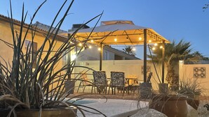 An outdoor patio area with a covered seating area, potted plants, and a stone pathway. - Spacious 3+3 w/ Pool & Game room, 5mins from Lake (Lake Havasu City)