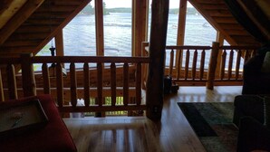 Eine Holzhütte mit einem Balkon mit Blick auf einen See.