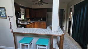 A kitchen with wooden cabinets, a white countertop, and a ceiling fan. There is a sign above the counter that reads "Welcome to our cabin."