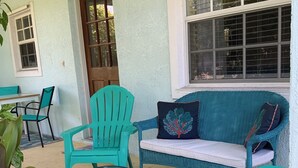 A covered patio area with turquoise chairs, a small round table, and a wicker sofa with a cushion. - Venetian Vacation! Close To Beaches, Restaurants & Shopping! (Venice)
