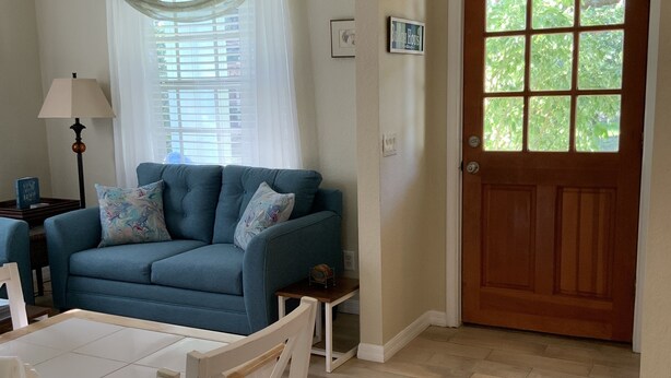 A living room with a blue sofa, a white table, and a wooden floor. - Venetian Vacation! Close To Beaches, Restaurants & Shopping! (Venice)