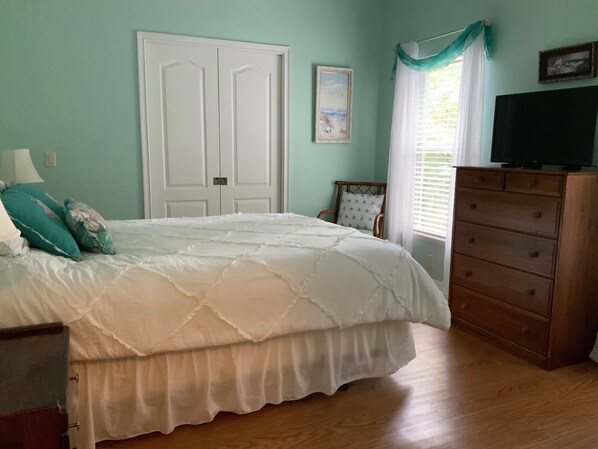 A bedroom with a bed, a dresser, a chair, and a television.