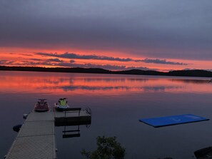 Un lac paisible au crépuscule, avec une jetée qui s’avance sur l’eau, agrémentée d’un banc et d’une trottinette.