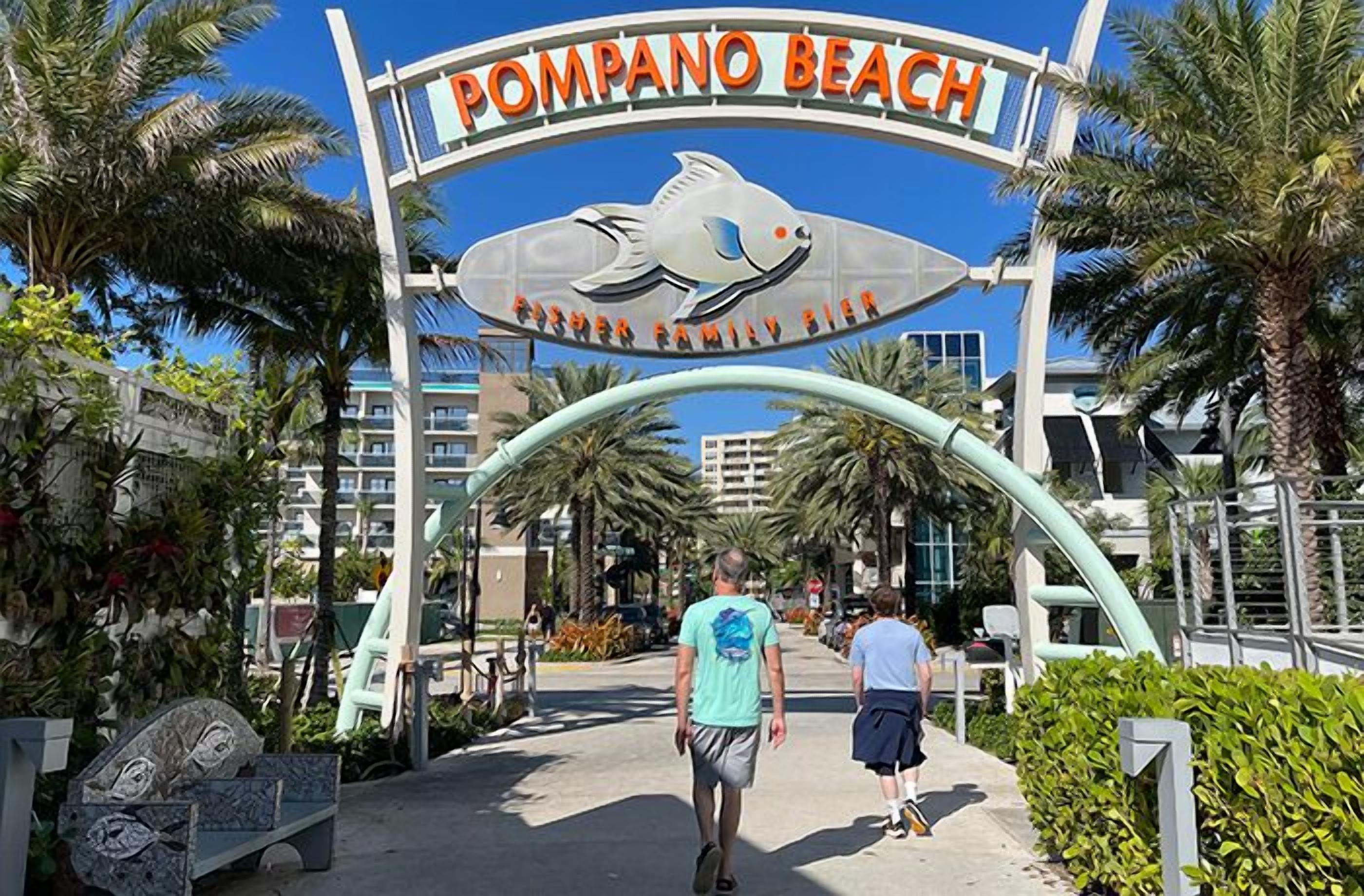 A sign for Pompano Beach with a fish logo and the text "Pompano Beach" and "Fisher Family Bier".