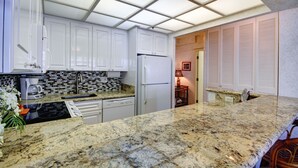 Een moderne keuken met witte kasten, een granieten werkblad en een geïntegreerde vaatwasser.