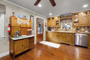 Kitchen with wooden cabinetry, stainless steel dishwasher, and a window offering a view of the outdoors.