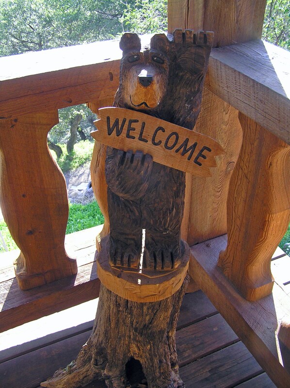 A wooden bear sculpture with a 'WELCOME' sign on a wooden deck. - Madera Canyon home w/ spectacular mountain view (Madera Canyon)