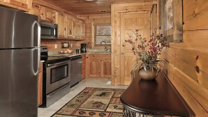Una cocina con armarios de madera, electrodomésticos de acero inoxidable, una cafetera y un florero con flores.