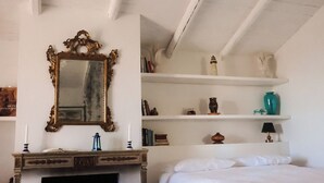 A bedroom with a bed, a vanity with a mirror, a fireplace, and a ceiling fan. - Mondomini - Charming cottage with view on the sea (Campofilone)