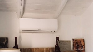 A room with a wooden desk, a white lamp, a white air conditioning unit, and a shelf with decorative items. - Mondomini - Charming cottage with view on the sea (Campofilone)
