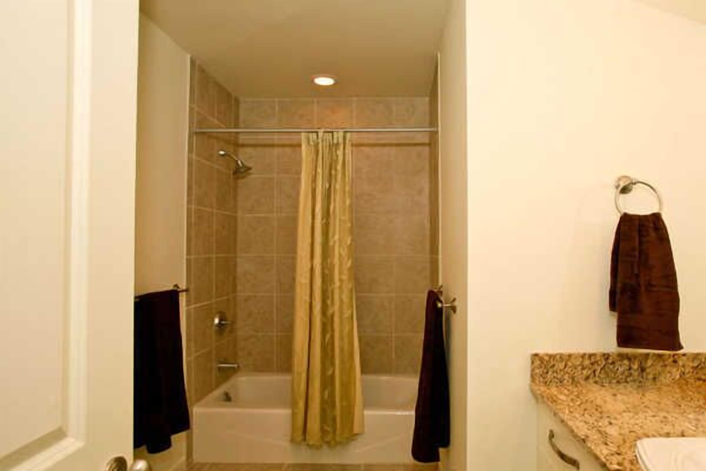 Un baño con ducha, bañera y tocador con perchero.