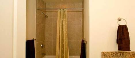 Un baño con ducha, bañera y tocador con perchero.