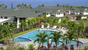 Ein Resort mit Swimmingpool, umgeben von Palmen und Liegestühlen, mit Blick auf den Ozean.