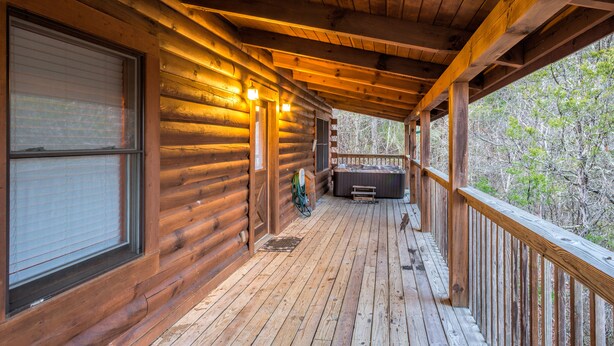 A wooden cabin with a covered porch, a hot tub, and a view of trees. - The Cabin at Eagle Feather - Hot Tub, Pool Table! Seasonal Pool Mountain View (Sevierville)