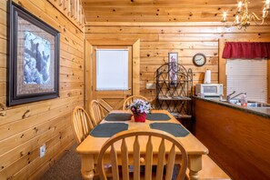 Cozy cabin interior with a dining table, kitchenette, and comfortable seating area.