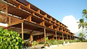 A beachfront hotel with a wooden structure, outdoor seating, and palm trees. - "THREE PALMS"~ON beach, remodeled, private patio, generator, pool, quiet & clean (St. Thomas)