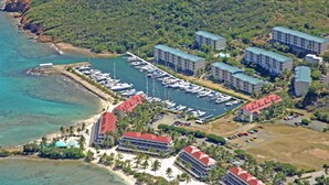 An aerial view of a coastal hotel with multiple buildings, a marina with boats, and a beach area. - "THREE PALMS"~ON beach, remodeled, private patio, generator, pool, quiet & clean (St. Thomas)