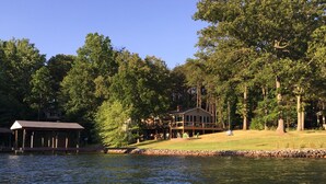 A lakeside cabin with a dock, surrounded by dense trees and a clear sky. - Flat Lot, Views! Waterslide, Firepit, Kayaks, Pickleball, Pingpong, Tennis, WiFi (Moneta)
