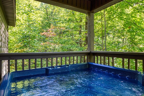 Relax in a serene hot tub surrounded by lush greenery and a natural setting.