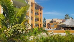 A resort with a pool area, palm trees, and a building with balconies. - VILLAS DE CORTEZ, Beachfront, 24 PICKLEBBALL CTS, Poolside, ,  1 BR Condo,  (Los Barriles)