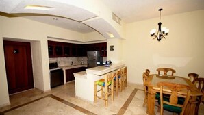 A kitchen with a central island, wooden dining table, and chairs. - VILLAS DE CORTEZ, Beachfront, 24 PICKLEBBALL CTS, Poolside, ,  1 BR Condo,  (Los Barriles)
