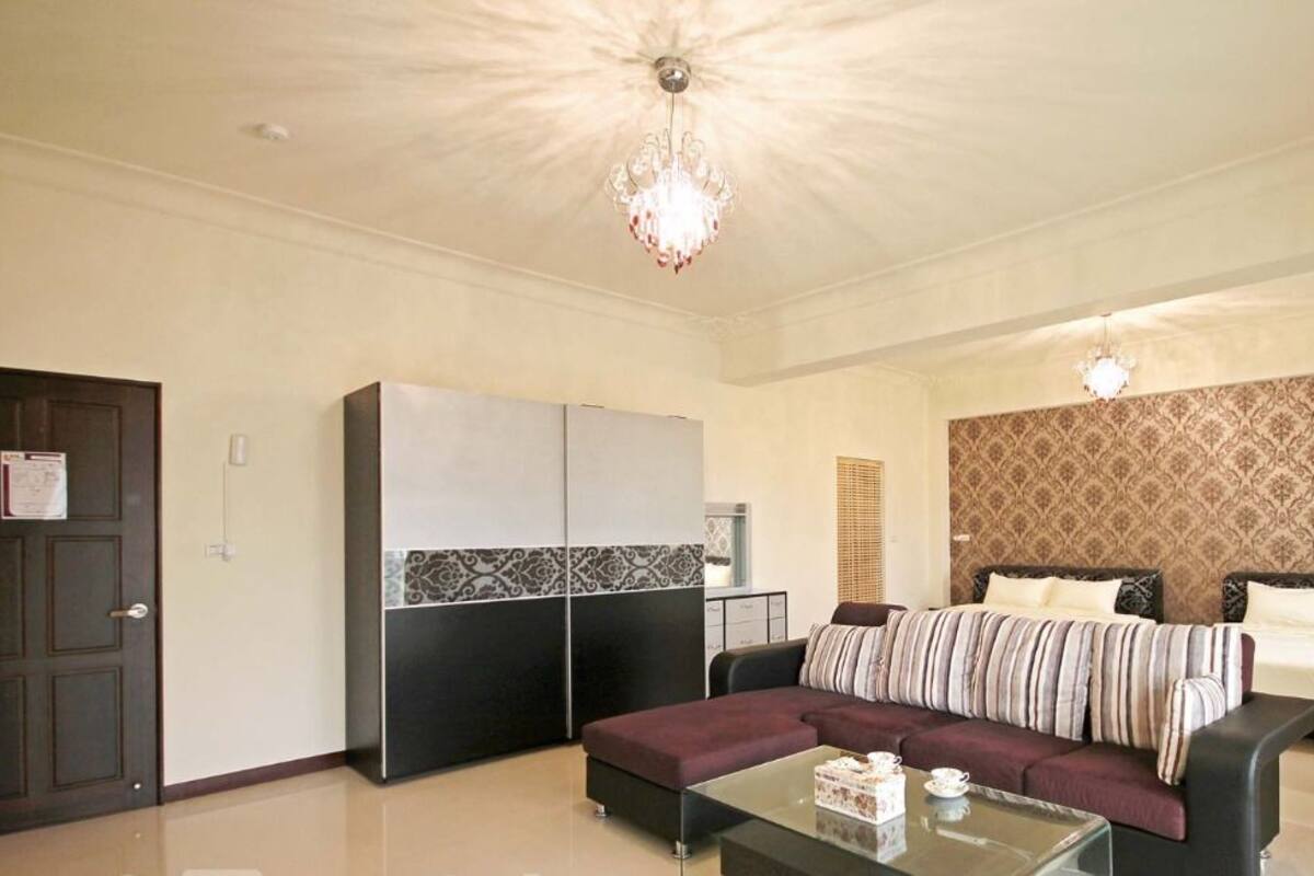 A spacious living room with a sofa, a coffee table, a bed, and a wardrobe.