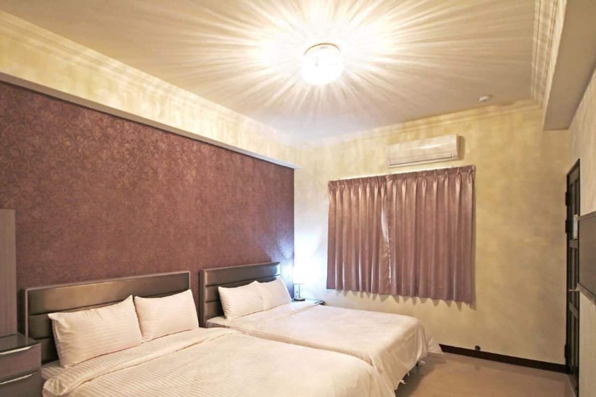 A hotel room with two beds, a large mirror, an air conditioning unit, and a television.