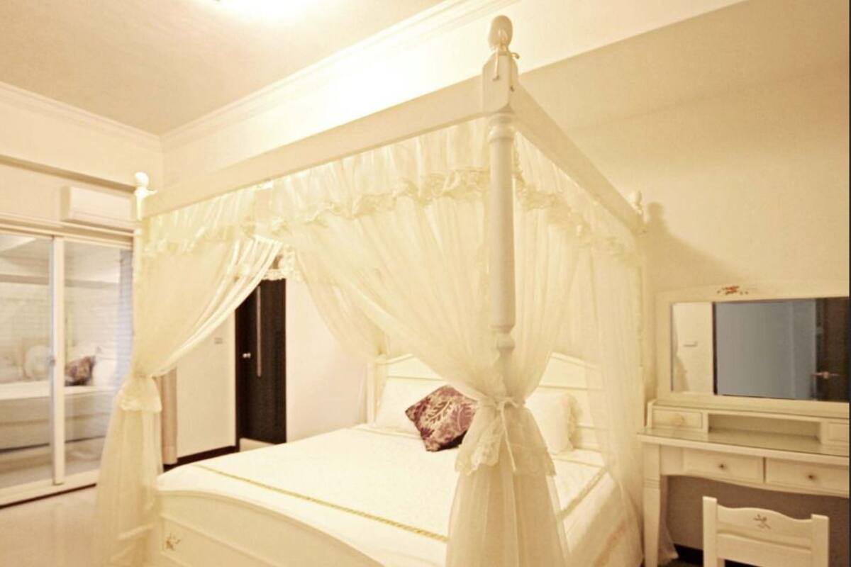 A bedroom with a four-poster bed, a wardrobe, and a mirror.