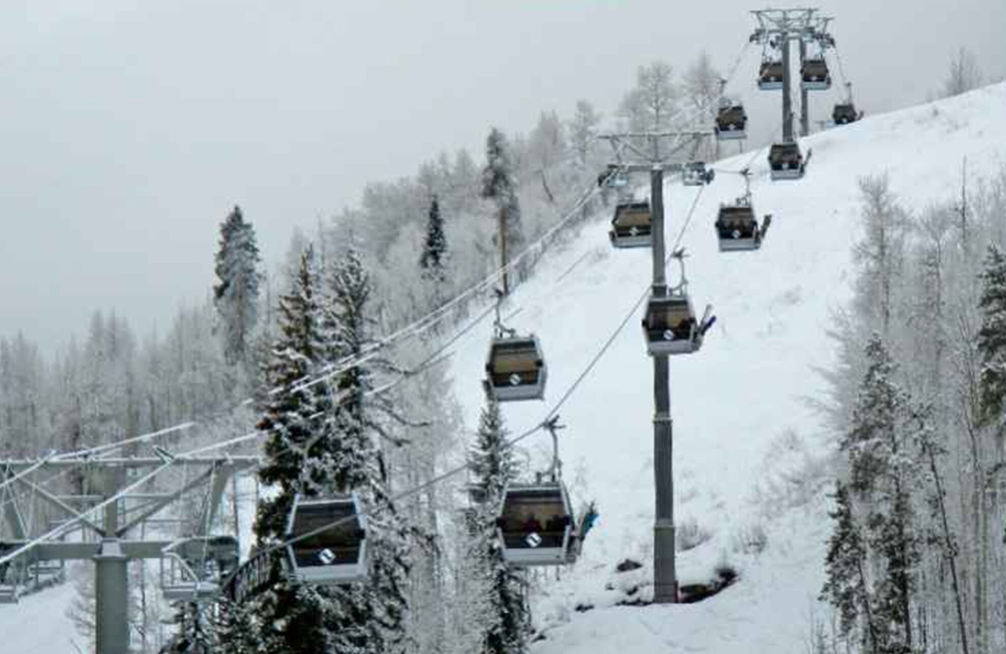 A ski lift with cabins ascending a snowy slope.