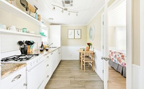 A kitchen with white cabinets, a gas stove, and a dining area with a table and chairs.