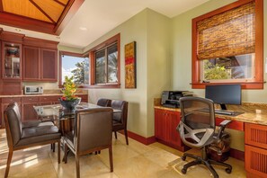 A modern kitchen with a dining area, wooden cabinets, a coffee machine, and a large window with a view. - Champion Ridge Home: Luxe w/ Private Pool,Spa,AC & Ocean/Mountain View (Kamuela)