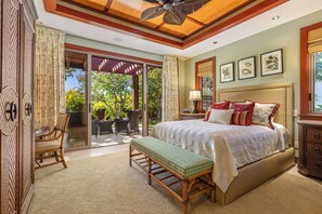 A bedroom with a large bed, a bench, a chair, and a sliding glass door leading to an outdoor area. - Champion Ridge Home: Luxe w/ Private Pool,Spa,AC & Ocean/Mountain View (Kamuela)