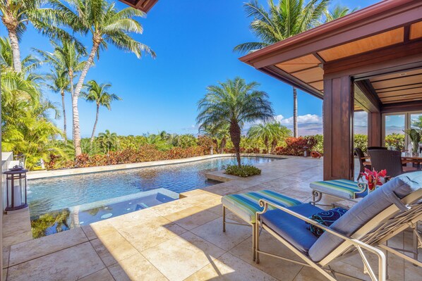 A pool area with lounge chairs, palm trees, and a view of the landscape. - Champion Ridge Home: Luxe w/ Private Pool,Spa,AC & Ocean/Mountain View (Kamuela)