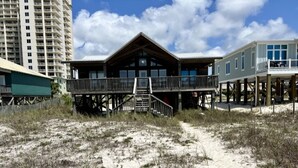 Una propiedad frente al mar con una estructura de madera que incluye un balcón y una terraza cubierta.