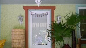 A room with a tiled floor, a large woven basket, a potted plant, and a door with a decorative curtain. - Beautiful Cozy Bedroom In Great B&B  Historic Home ~ Close To The City Center  (Miami)