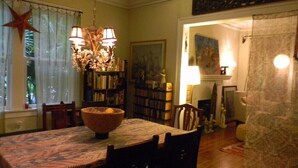 A dining area with a round table, chairs, a chandelier, and a bookshelf. - Beautiful Cozy Bedroom In Great B&B  Historic Home ~ Close To The City Center  (Miami)