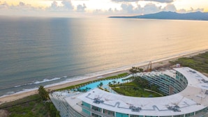 Et resort med pool, beliggenhed ved stranden og en stor bygning med flere etager.