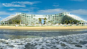 Et stort, moderne hotel med en buet facade, flere balkoner og beliggenhed ved stranden.