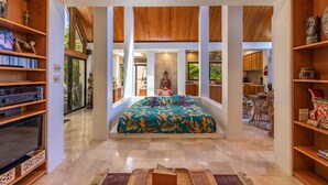 Una habitación espaciosa con una cama grande, estanterías de madera y vistas al exterior.