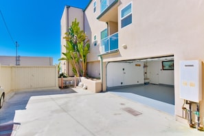 Stylish residential building with a garage entrance, garden, and white fence.