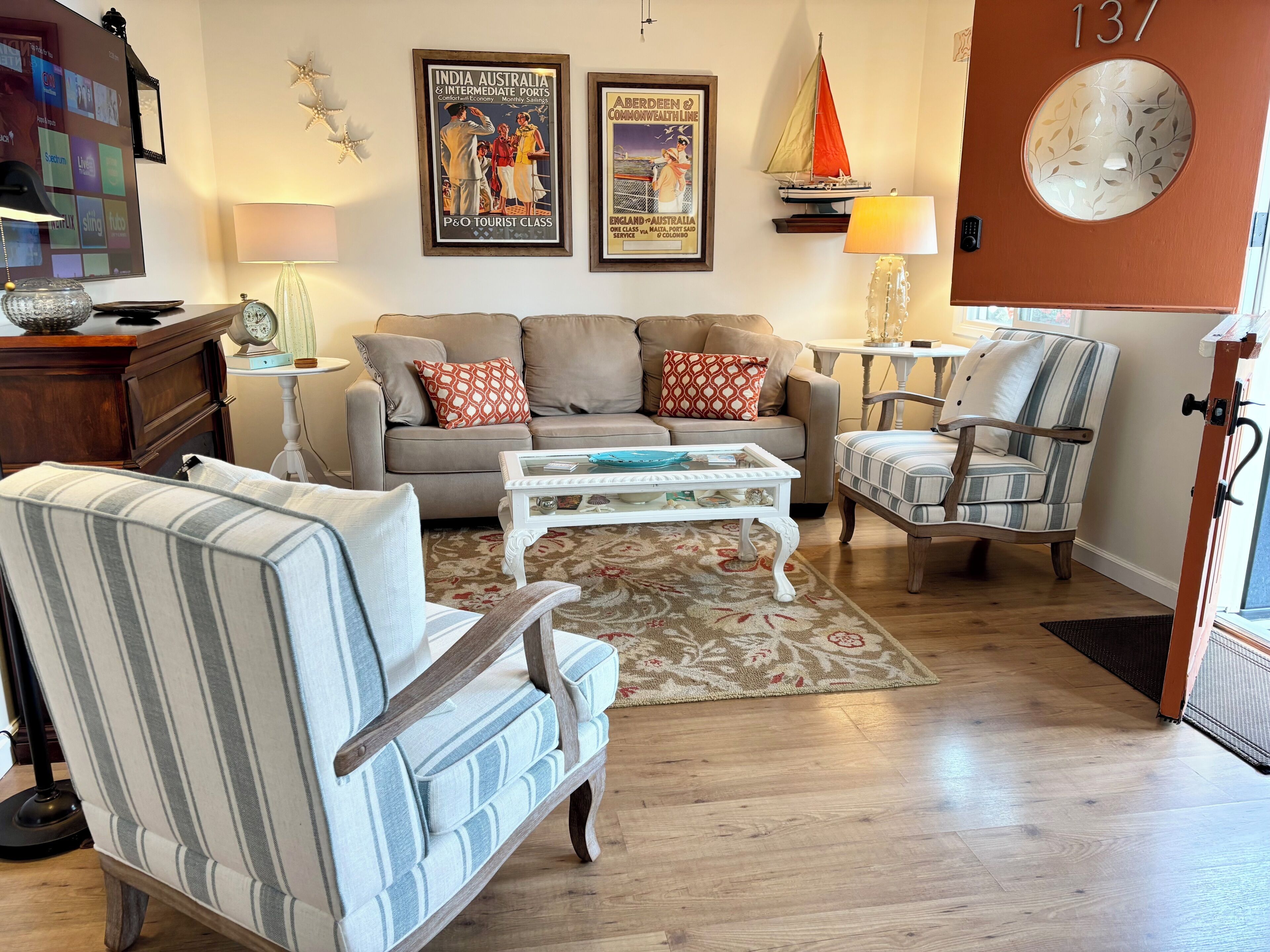 Una sala de estar con sofá, sillón, mesa de centro y un modelo decorativo de un velero.