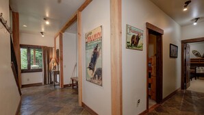A hallway with stone flooring, wooden beams, and two posters on the walls.