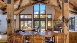 A spacious dining area with wooden furniture and large windows offering mountain views.